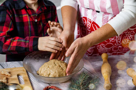 Christmas baking preparation. Close-up of woman and child's hand bake gingerbread and biscuits.の写真素材