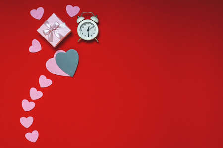 Top view of workspace time for valentines day flat lay on red background, heart gifts and alarm clock, copy space.の写真素材
