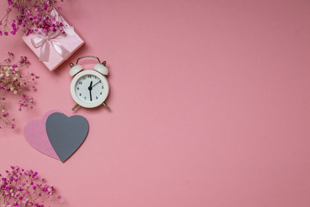 Flat lay for valentine's day: gift, alarm clock and hearts on a pink background. view from above.の写真素材