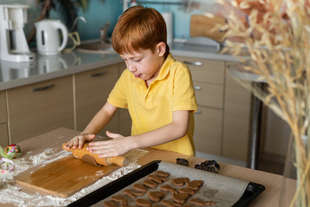 Child red-haired boy prepares Easter cookies in the kitchen. The concept of cooking at home lifestyle series photo.の写真素材