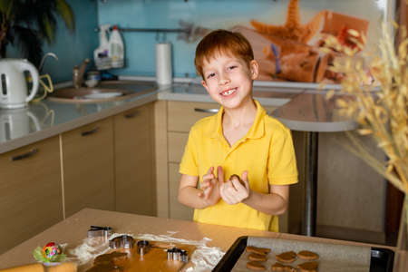 Preparing for Easter baking. Portrait of a child looking at the camera and smiling red-haired boy makes dough for baking cookies. Easter food concept.の写真素材