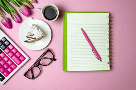 Flat lay view of Workspace notepad and pen, financial sphere calculator, festive view of tulips,...