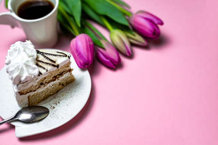 Close-up sweet black coffee cake and lilac tulips on a light pink background, close-up. Greeting card with place for text, copy space.の写真素材