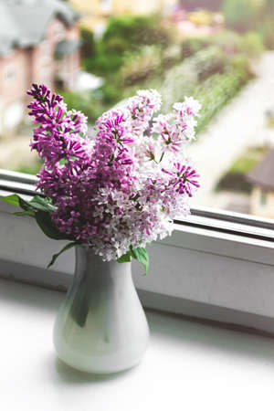 Still life on the windowsill blooming lilac in a white vase. Spring flowers, retro style.の写真素材