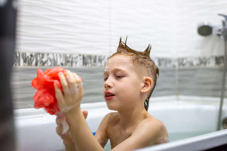 Personal hygiene, red-haired boy child washes himself in the bathroom.