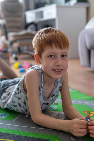 Young child boy plays constructor at home on the floor. preschool education. home fun. Lying on the...