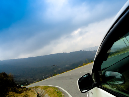 Car driving down a mountain roads on a cloudy dayの写真素材