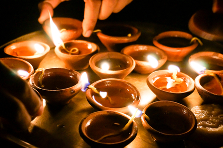Hands lighting and picking up earthenware diwali lampsの写真素材