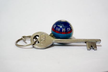 Key with a globe shaped compass keychain  May be used to denote a key to travel, explore, adventure,...