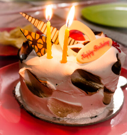 Decorated birthday cake with candles and colorful platesの写真素材