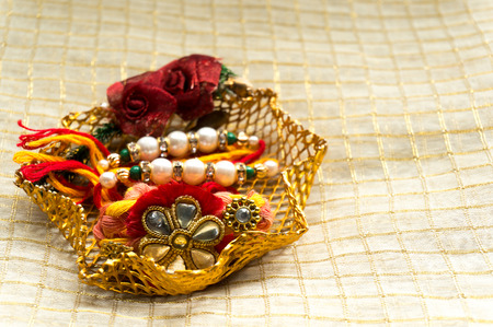 rakhi wrist band with the traditional tilak and rice, in a golden mesh holder. This hindu festival celebrates the bond and duty of brothers and sistersの写真素材
