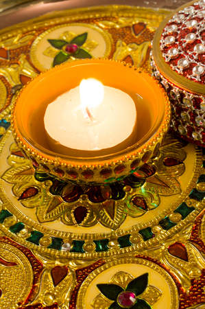 Traditional diwali diya lamp lit and placed on a beautifully decorated and carved golden plateの写真素材