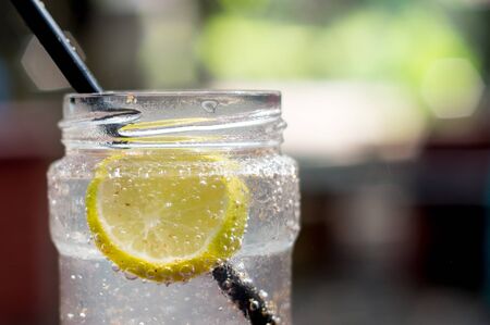 Lemonade bottle with straw and lemon slice. Background is out of focus to give a pleasing effect