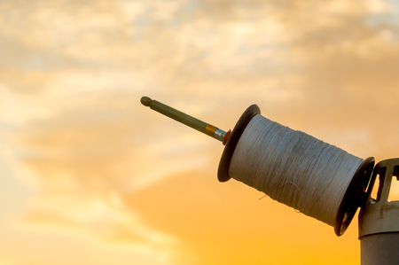 Indian spool, charkhi, used in the sport of kit fighting set against a colorful out of focus background. The thread shown here is the non abrasive or cutting sadda thread.の写真素材