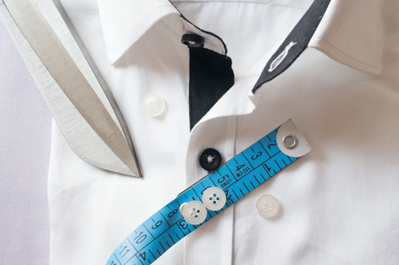 High key white shirt with measuring tape and scissors showing fitting, design, perfect fit and tailoring.の写真素材