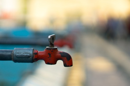 Dry old red tap with blurred background showing water shortage and need for clean waterの写真素材