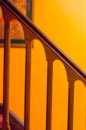 Polished wooden railing against an orange wall. Interiors for an elegant mansion of architectural beautyの写真素材