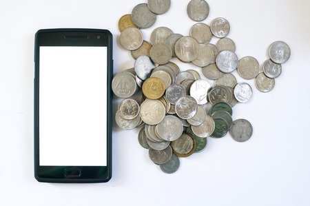Mobile phone with indian currency set on a white background. Denoting payment through mobile and mobile wallets. Pile of old and new coins with phoneの写真素材