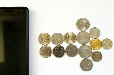 Arrow of coins from mobile phone. Mobile phone with indian currency set on a white background. Denoting payment through mobile and mobile walletsの写真素材