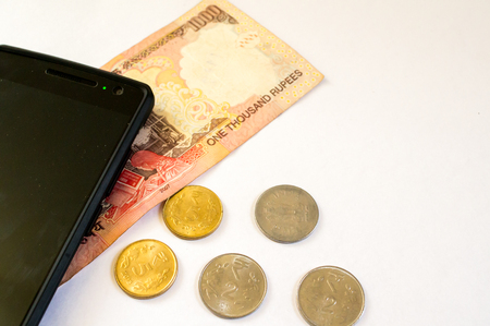 Mobile phone with indian currency set on a white background. Denoting payment through mobile and mobile walletsの写真素材