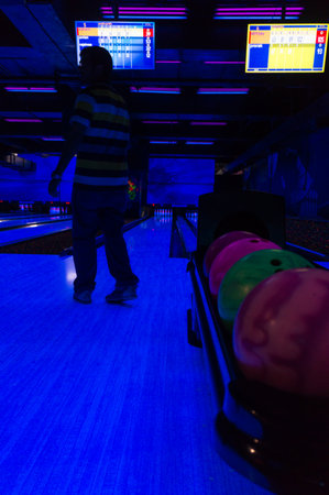 Delhi, India - 30th July 2016: Person looking at a bowling alley after throwing a ball. The neon balls are visibile in the amazing black light as are the scoresのeditorial素材