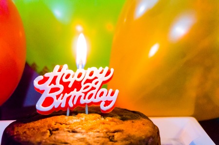 Healthy homemade cake with candle, balloons ready for a partyの写真素材