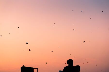 Silhouette of people flying kites at sunset in Jaipur on Makar Sankranti. The sky is filled with kitesの写真素材