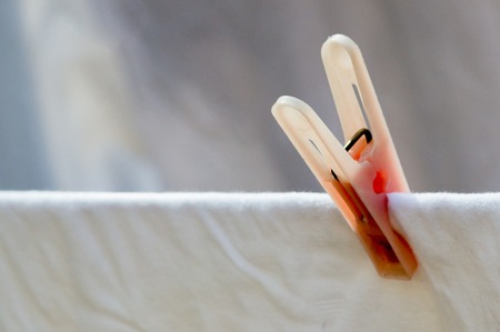 Minimalistic shot of a laundry clip holding a white sheet. Perfect for denoting chores and cleanlinessの写真素材