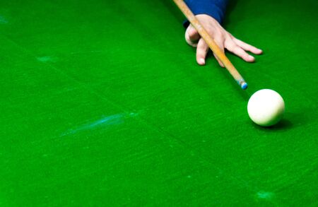 hand supporting a stick as it is lined up for a shot in billiards, pool or snooker