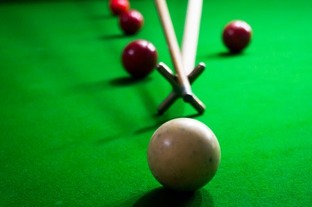 Using a spider stick to take a long shot in a game of snooker pool or billiards
