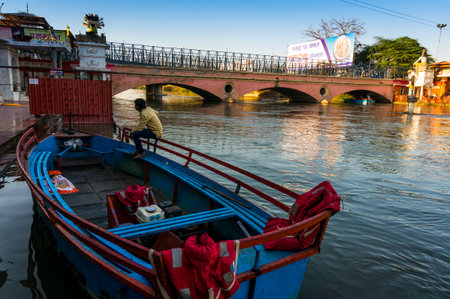 Delhi, India - 05th Mar 2017: Boatsman sitting on a boat on the bank of the river ganga, overlooking a templeのeditorial素材