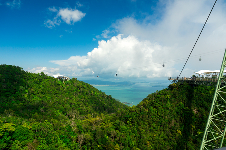 Cable car going down to another tree covered mountainの写真素材