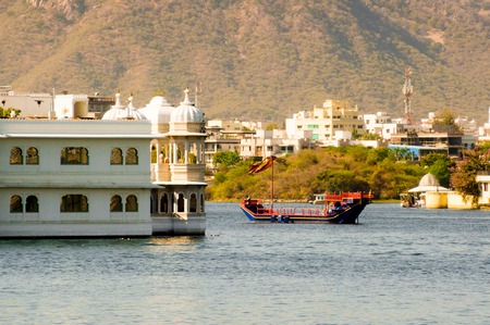 Ornate boat passing near a palace on a lakeの写真素材