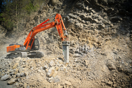 Construction excavator clearing up rocks from a landslide