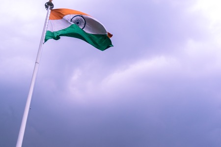 Indian tricolor fluttering in the wind against a cloudy skyの写真素材