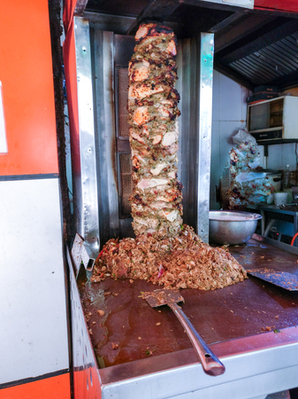 Roadside stall in india making Shwarma on a vertical grill out of a mix of lamb, chicken meat in an old grill. This is fast becoming a popular snack in indiaの写真素材