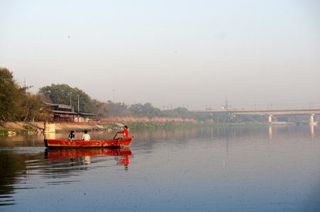red boat rowing into the middel of a river early in the morning in the middle of seagulls