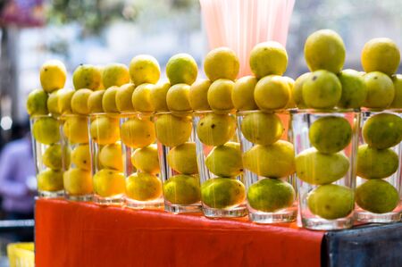 Lemons placed in glasses on a street cart serving lemonade placed on a red cloth. These refreshing...