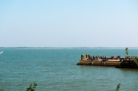 Diu, Gujarat, India - Circa 2018 : People, men, women, children walking on a stone jetty at Diu fort...