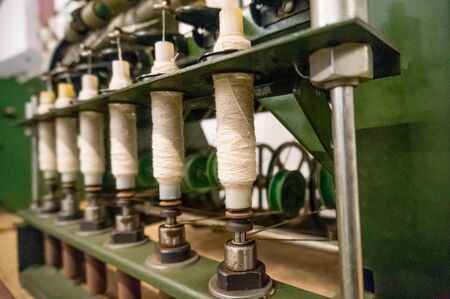 Green spindle weaving machine used to make cloth.  The multiple spools of thread and the mechanized system helps make the cloth making process easier and fasterの写真素材