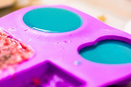Blue soap setting in a purple silicon mold of various shapes