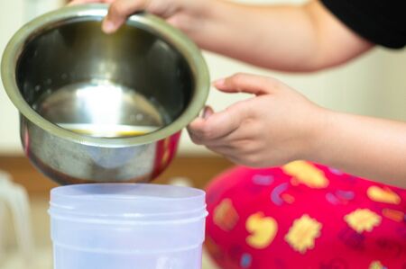 Pouring an oil mix from a steel container into a plastic container for cooking, soap making and home...