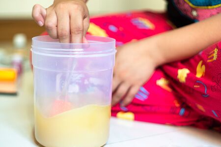 Young girl mixing a solution of oil and lye undergoing saponification in a transparent container for making home made soapの写真素材