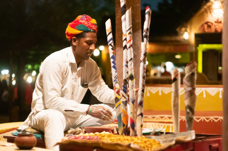 Colorfully dressed rajasthani man in white kurta and turban serving bhel puri in paper conesのeditorial素材