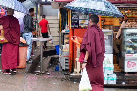 bhuddhist monks walking on teh street with umbrellas in the monastries of Dharamshalaのeditorial素材