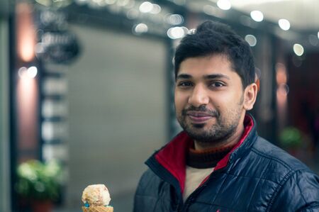 Young indian man in black and red jacket in a shopping mall
