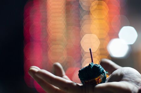 Human hand holding green sutli rassi bomb in front of out of focus lights with a hexagon bokehの写真素材