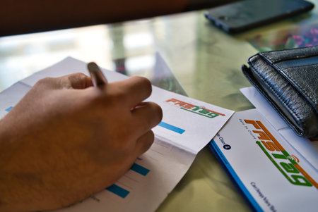 Gurgaon - India, Circa 2019: Photograph of Fast Tag application form being filled with a fountain pen, along with a wallet and a mobile phone on a beautifully decorated table. Fast tag is expected to make toll stops cash and hassle free and was implementeのeditorial素材