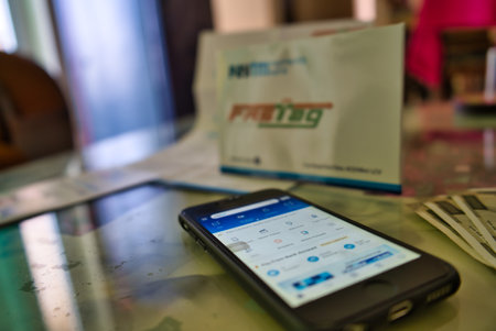 Gurgaon - India, Circa 2019: Photograph of Fast Tag on a beautifully crafted table along with a mobile phone on the table, the application form provided by PayTM payment bank. Fast tag is expected to make toll stops cash and hassle free and was implementeのeditorial素材