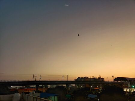 Jaipur, Rajasthan Circa 2020 - Photograph showing a metro train leaving its metro station during dusk on a cold winter chilling evening with a lot of surrounding trees and housesの写真素材